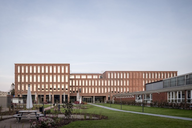 Rückansicht der modernen Firmenzentrale von Queisser Pharma mit begrüntem Innenhof im Vordergrund.