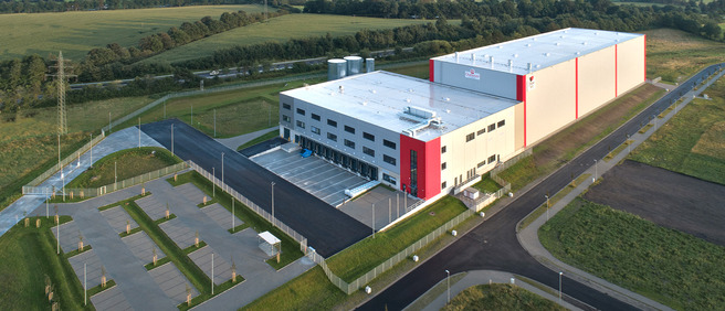 Luftaufnahme des Queisser-Logistikzentrums Stand September 2019 mit Ladebereichen, leerem Parkplatz und umliegender Grünfläche 