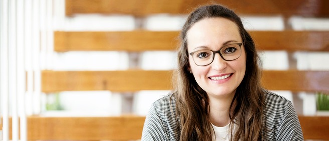Lächelnde Mitarbeiterin mit Brille im modernen Innenraum