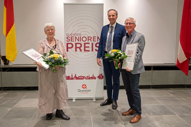 Geschäftsführer Erich Nobis mit den beiden Preisträger*innen des Queisser Seniorenpreises 2024 vor einem Roll-Up mit dem Schriftzug "Queisser Senorenpreis"